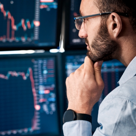 Man monitoring graph data on multiple screens